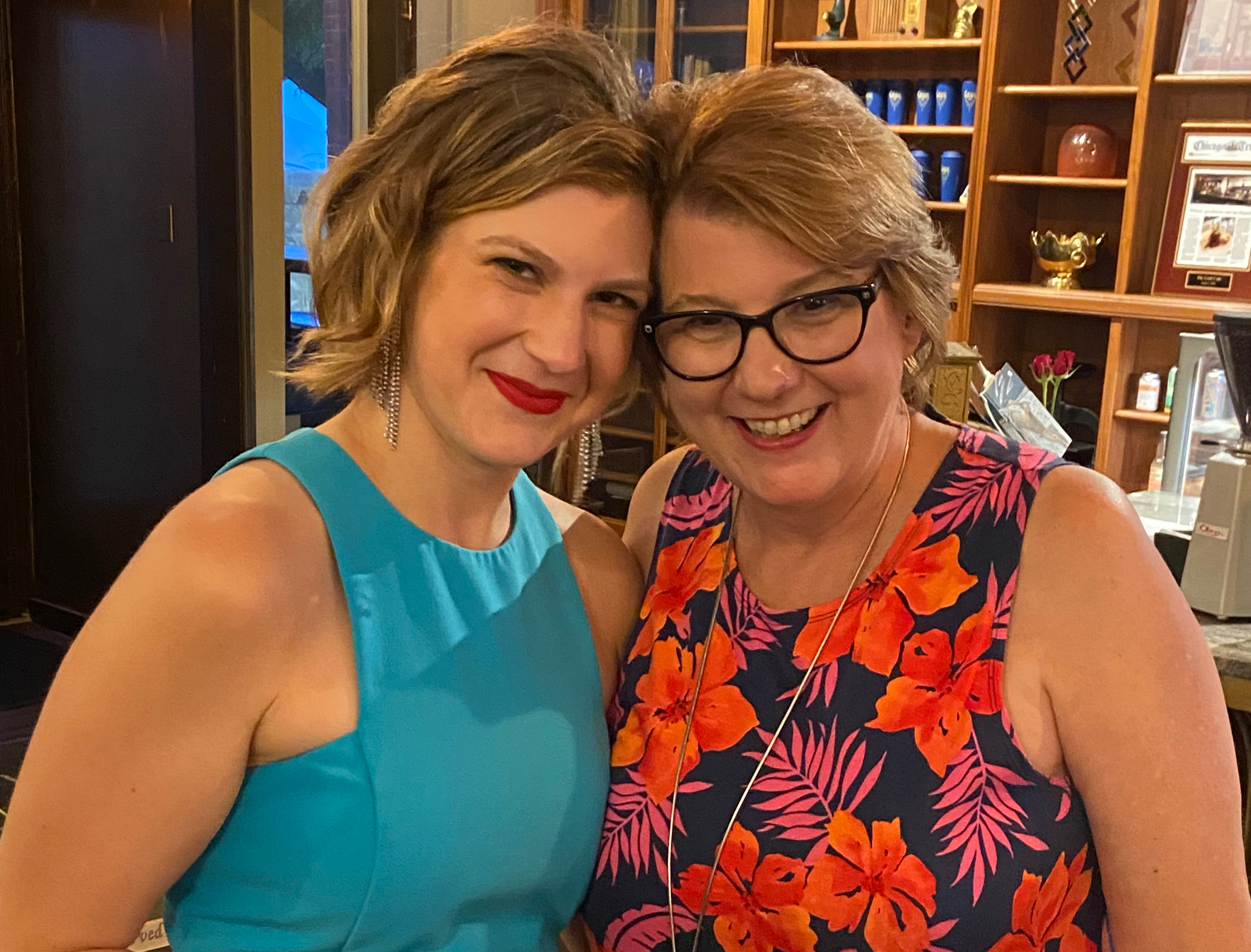 Kate stands on the left in a blue top. Her mom is to the right in a floral dress.